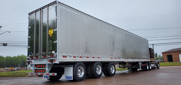 Vanguard refrigerated trailer hitched to a brown tractor on a wet lot, rear three-quarter view