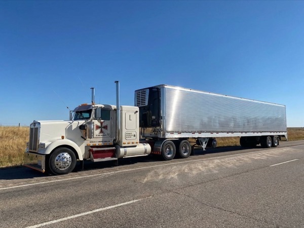Classic tractor and Vanguard reefer trailer on a sun-baked interstate under clear summer sky