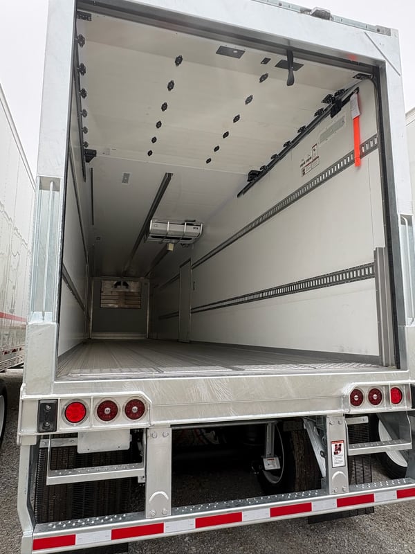 Rear straight-on view of a Vanguard reefer with swing doors open, showing the full interior cargo box — ceiling evaporator, logistics tracks down both walls, and aluminum floor