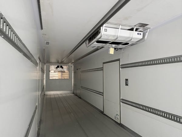 Inside a McLean refrigerated trailer body showing the reefer unit, side door, and E-track walls