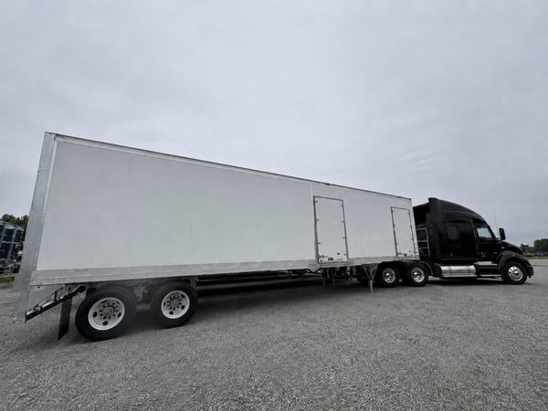 White Vanguard reefer trailer with a side delivery door, paired with a black tractor