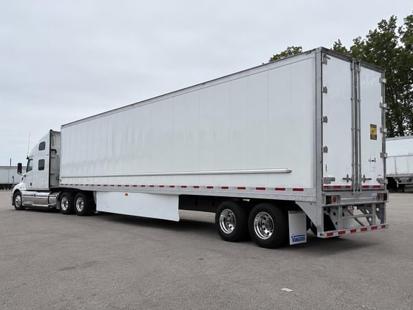 White Vanguard reefer trailer with a white tractor, rear three-quarter view in a paved lot