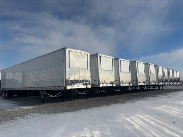 A long row of finished Vanguard refrigerated trailers staged in the yard under a winter sky