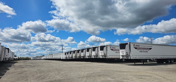 A long row of Vanguard reefer trailers in a customer fleet yard under a blue sky